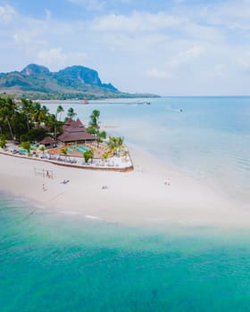 Top view at Koh Muk a tropical island with palm trees and soft white sand, and a turqouse colored ocean, sandbar in the ocean in Koh Mook Trang Thailand