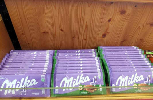 An array of Milka chocolate bars neatly organized on the shelves of a supermarket, showcasing the popular confectionery brand.