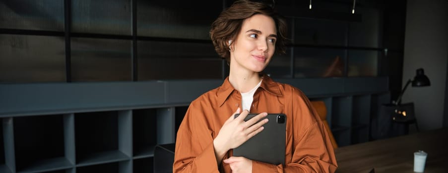 Portrait of young woman, company employee, office worker in casual clothes working with tablet in conference room, planning team meeting.