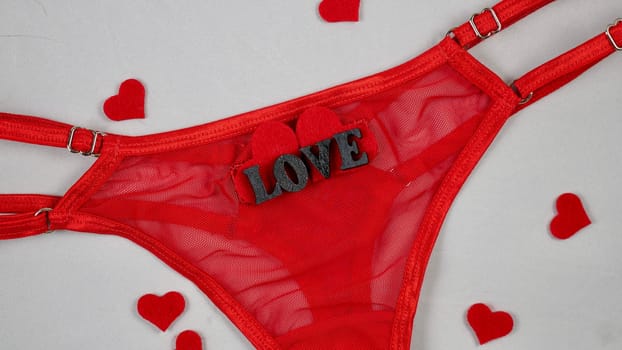 Valentine's Day Sexy Underwear Red Mesh Micro Panties Thong Hold Up String. Close-up in focus on white isolated background. with hearts