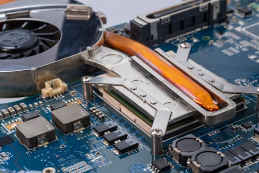 Laptop CPU and cooling technology. A detailed shot of a computer motherboard, featuring a CPU, chipsets and circuit board showcasing the intricate engineering and composite materials used in its manufacturing. Selective focus