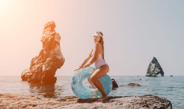 Woman summer sea. Happy woman swimming with inflatable donut on the beach in summer sunny day, surrounded by volcanic mountains. Summer vacation concept