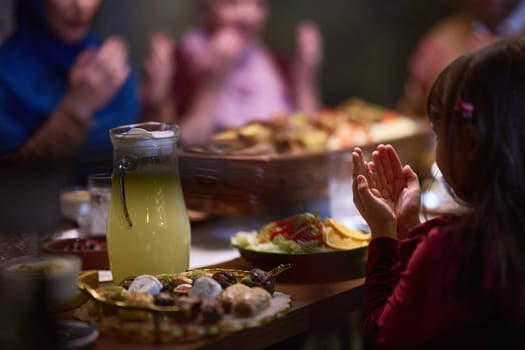 A young girl raises her hands in prayer as she prepares for her iftar meal during the holy month of Ramadan, embodying spiritual devotion and innocence