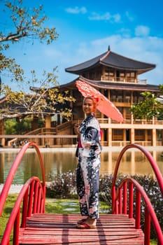 Asian girl in kimono and umbrella in Japanese theme park Hinoki Land in Chai Prakan District, Chiang Mai