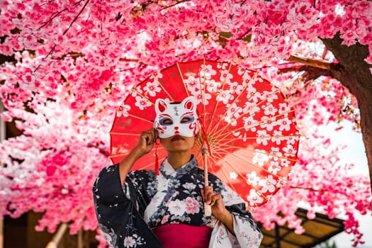 Asian girl in kimono and umbrella in Japanese theme park Hinoki Land in Chai Prakan District, Chiang Mai