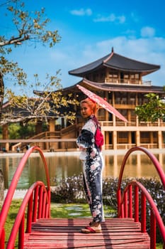 Asian girl in kimono and umbrella in Japanese theme park Hinoki Land in Chai Prakan District, Chiang Mai