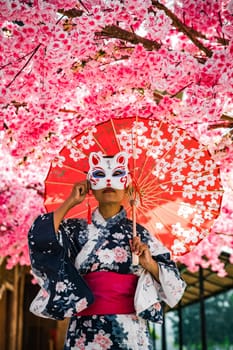 Asian girl in kimono and umbrella in Japanese theme park Hinoki Land in Chai Prakan District, Chiang Mai