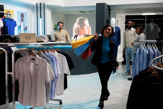 Clothing store satisfied customer walking with shopping bags in clothing store and looking at camera. Cheerful smiling asian woman carrying paper bags with trendy apparel purchase in mall