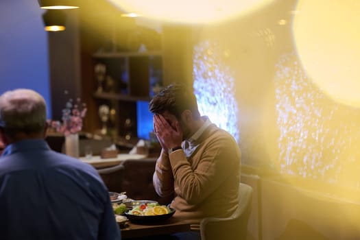 In a modern restaurant setting, a European Islamic family comes together for iftar during Ramadan, engaging in prayer before the meal, uniting tradition and contemporary practices in a celebration of faith and family.