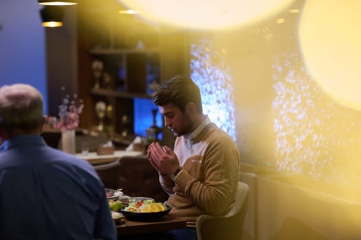 In a modern restaurant setting, a European Islamic family comes together for iftar during Ramadan, engaging in prayer before the meal, uniting tradition and contemporary practices in a celebration of faith and family.