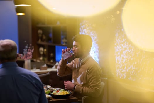 A son and his elderly father engage in heartfelt conversation while patiently awaiting their iftar meal, fostering intergenerational bonding and cherished moments of family connection.