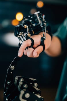 At a technical college a teen boy tests a robot hand and arm touching fingers for educational development. Embracing AI humanity and innovative learning.