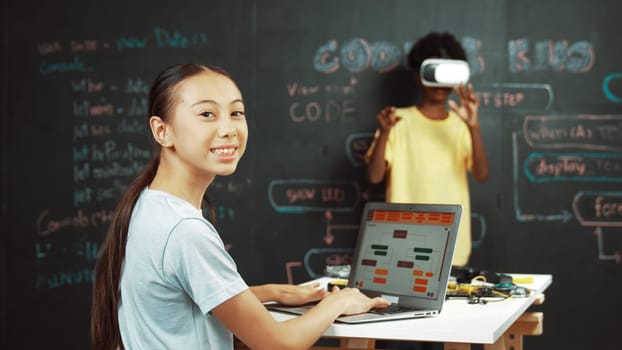 African boy using VR glasses while young woman looking at camera and coding or programing system. Smart teenager standing at blackboard while touching in simulate program at STEM class. Edification.