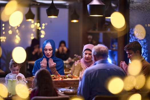 In a modern restaurant setting, a European Islamic family comes together for iftar during Ramadan, engaging in prayer before the meal, uniting tradition and contemporary practices in a celebration of faith and family.