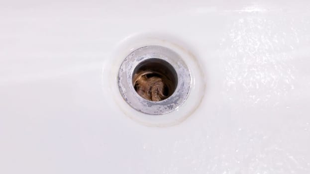 Closeup Clogs In Drain, Hair Loss, Hair Fall. Big Tuft Of Blond Hair In White Bathtub Hole Of Bathroom, Shower. Clogged Pipe. Plumbing Difficulties At Home. Thin Hair Problem. Horizontal Plane.