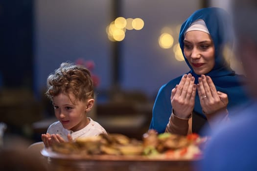 In a modern restaurant setting, a European Islamic family comes together for iftar during Ramadan, engaging in prayer before the meal, uniting tradition and contemporary practices in a celebration of faith and family.