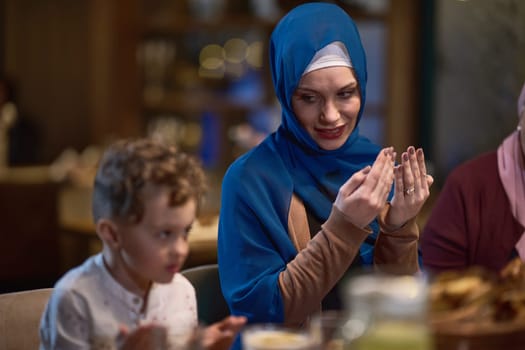 In a modern restaurant setting, a European Islamic family comes together for iftar during Ramadan, engaging in prayer before the meal, uniting tradition and contemporary practices in a celebration of faith and family.