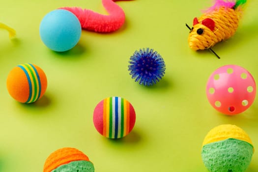 Colorful pet toys balls on green background close up