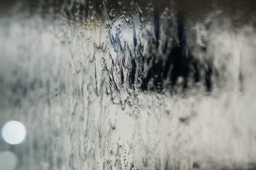 In a close-up capture, the texture of glass through which water flows is beautifully depicted, showcasing intricate patterns and the fluidity of movement in a mesmerizing display.