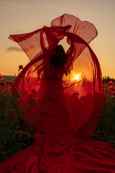 Woman poppy field red dress sunset. Happy woman in a long red dress in a beautiful large poppy field. Blond stands with her back posing on a large field of red poppies.