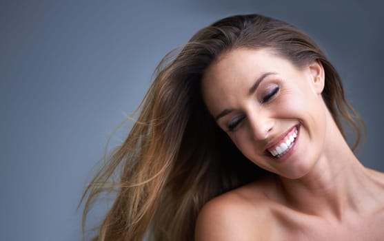 Hair, beauty and happy woman in studio with cosmetics, shampoo or treatment results on grey background. Haircare, smile and model with growth, shine or texture satisfaction or clean scalp confidence.