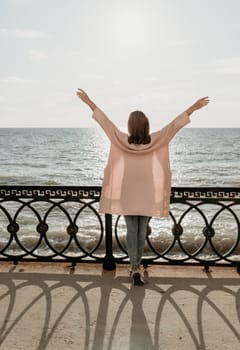 Woman travel sea. Young Happy woman in a long red dress posing on a beach near the sea on background of volcanic rocks, like in Iceland, sharing travel adventure journey