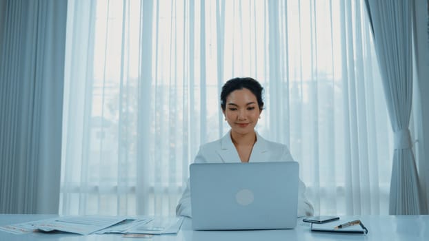 Young businesswoman sitting on the workspace desk using laptop computer for internet online content writing or secretary remote working from home. Vivancy