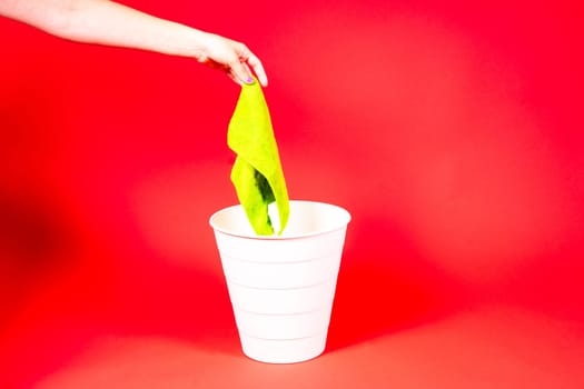 Throw napkin in a trash bin, house cleaning rag in hand in front of trash can, cleaning concept