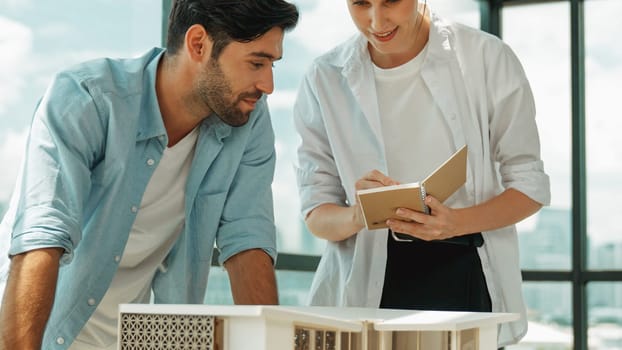 Skilled architect engineer team discussion about house model construction. Smart interior designer sharing, talking about building design while beautiful coworker taking a note. Design. Tracery