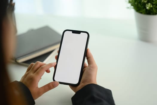 Cropped shot young businesswoman using mobile phone on white office desk.