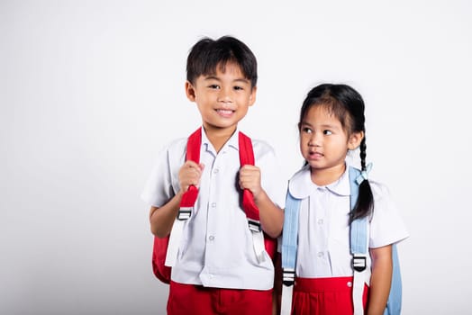 Two Asian student kid girl boy schoolchildren brother sister smile happy wear student thai uniform red pants skirt in studio shot isolated on white background, Portrait little children girl preschool