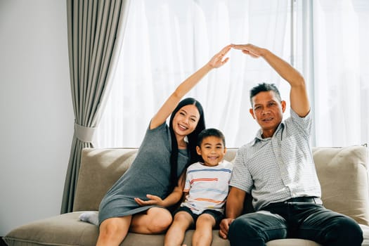 A happy family of four on a sofa parents forming a roof above their little son. Signifying house insurance children protection and future plans emphasizing family security.