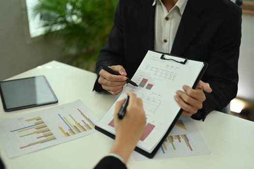 Businesspeople analyzing marketing research results or statistics data at meeting table.