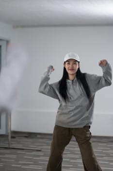 Shot of cheerful young woman wearing hoodie dancing hip hop dance in studio.