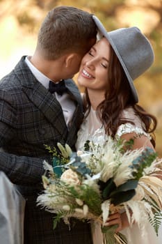 beautiful happy stylish bride in hat and groom laughing outdoor
