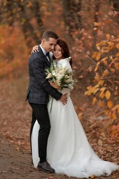 beautiful sensual bride in white wedding dress and groom standing outdoor on natural background