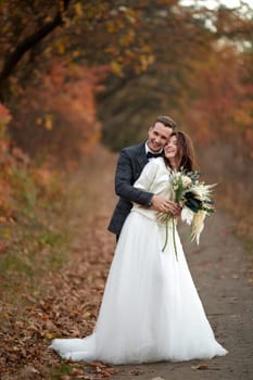 beautiful sensual bride in white wedding dress and groom standing on natural background