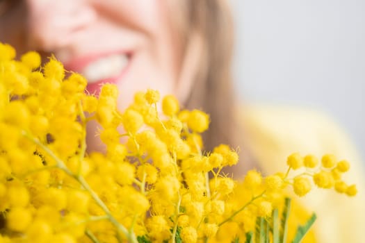 Beautiful young woman with mimosa flowers on white background. Close up