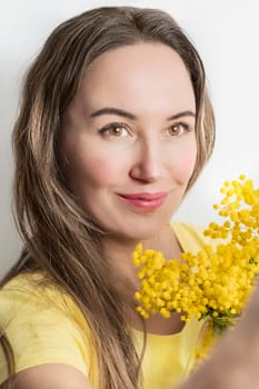 Beautiful young woman with mimosa flowers on white background. Close up