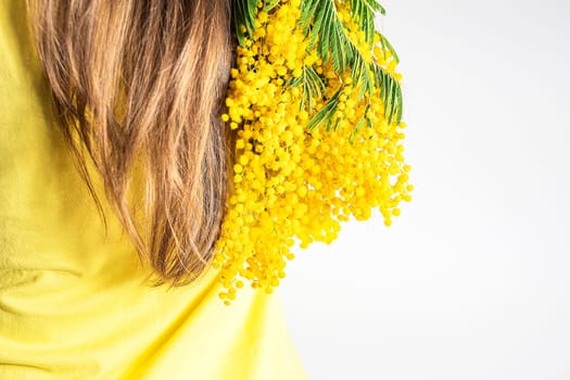 Close-up back brown hair with bouquet of yellow mimosa. Concept Health and hair care.