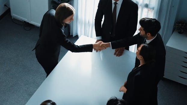 Top view of professional business team shaking hand and clapping hands to celebrate young businesswoman getting promotion. Diverse business people congratulate for successful project. Directorate.