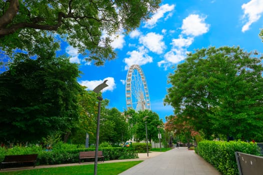 Big, tall white Ferris wheel in front of perfect blue sky. Happy summer vacation feelings.