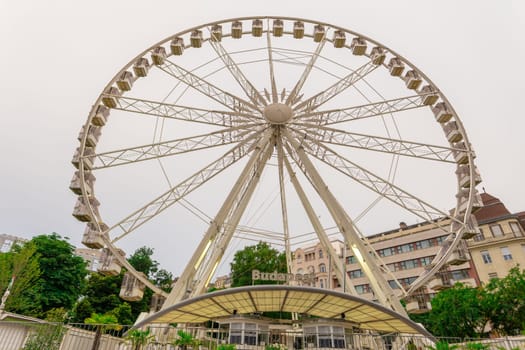 Big, tall white Ferris wheel in front of perfect blue sky. Happy summer vacation feelings.