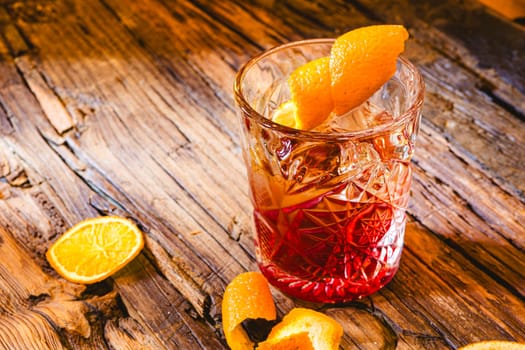 Delicious old fashion cocktail in the etched glass with ice and orange slices, dark wooden background. Shallow dof.