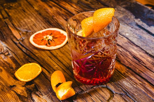 Delicious old fashion cocktail in the etched glass with ice and orange slices, dark wooden background. Shallow dof.