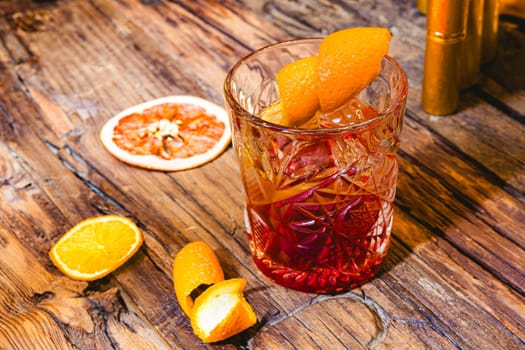 Delicious old fashion cocktail in the etched glass with ice and orange slices, dark wooden background. Shallow dof.