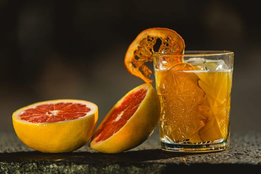 Delicious old fashion cocktail in the etched glass with ice and orange slices. Shallow dof