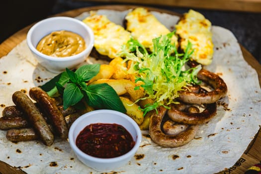 German style grilled sausages with potato wedges and bread with cheese and sauces close-up on a wooden tray on the table. Shallow dof