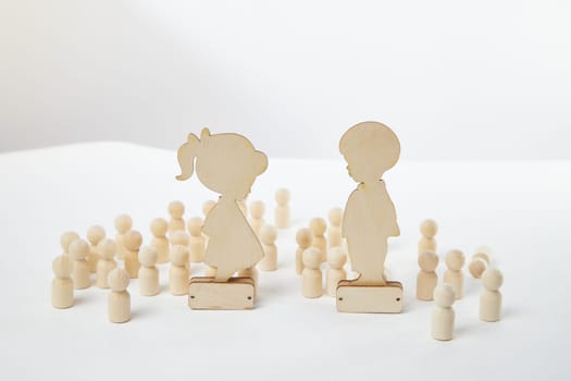 Wooden figures of a girl and a boy against a background of faceless people. A couple in love does not notice anyone around. Love is the most important thing