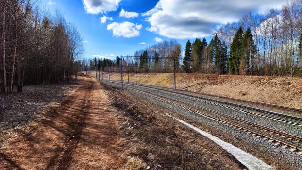 Railway track in the spring forest with blue sky. Concept of travel and trip